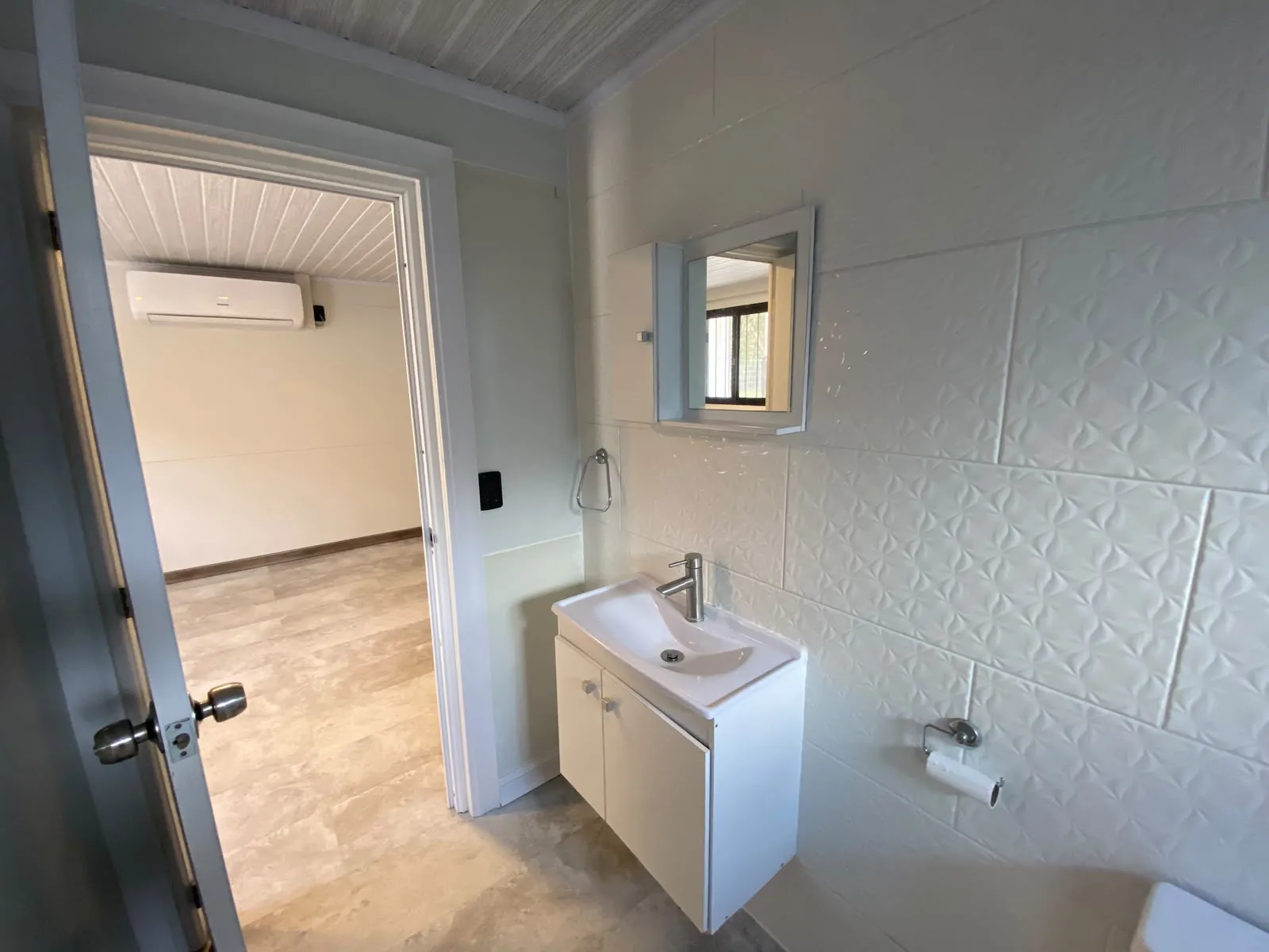Baño con revestimiento blanco en relieve y vanitory