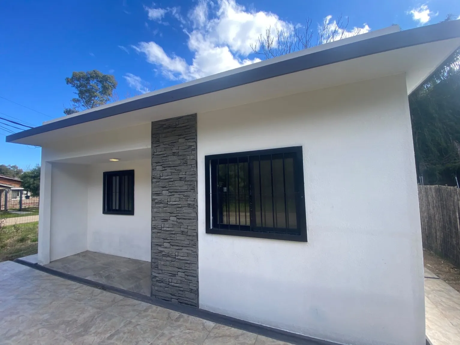 Fachada con columna símil piedra y aberturas negras
